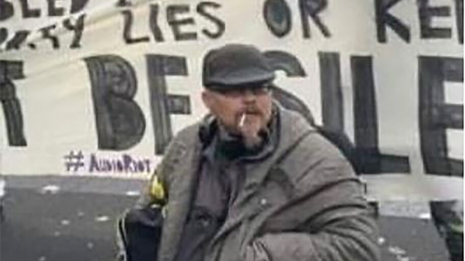Andy at a protest wearing a hat and a grey jacket.